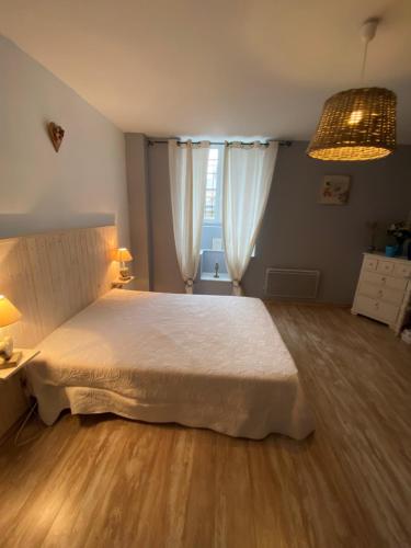 - une chambre avec un grand lit blanc et du parquet dans l'établissement La Glycine, à La Canourgue