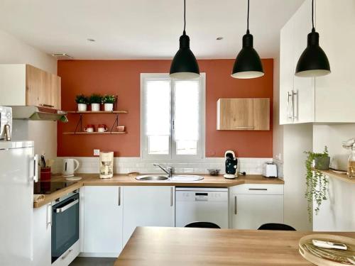 una cocina con armarios blancos y una pared de color naranja en Caporizon-La Marote-Gite calme tout neuf, en Lanobre