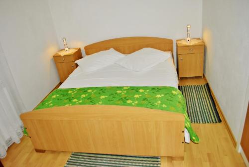 a wooden bed in a bedroom with two night stands at Apartments Buljevic in Vrboska