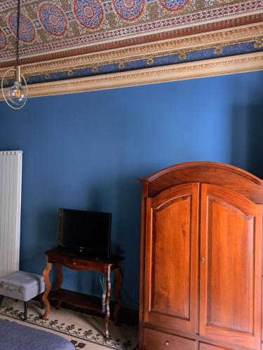 a blue room with a wooden cabinet and a television at Vera Rooms in Catania