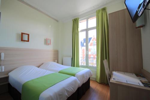 een hotelkamer met 2 bedden en een raam bij Hôtel De La Cathédrale in Reims