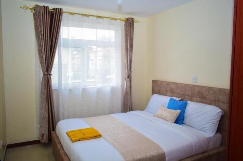 a bedroom with a large bed with a window at Havan Furnished Apartments-Milimani N8 in Nakuru