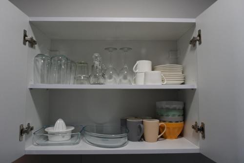 a cupboard filled with lots of dishes and glasses at KORZO SUITES PACEVILLE in St Julian's