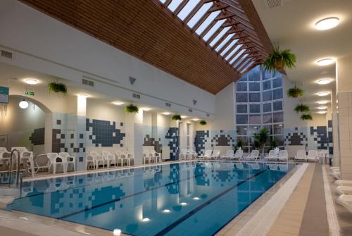 a large swimming pool with chairs and tables in a building at Pensiunea Flora in Băile Tuşnad