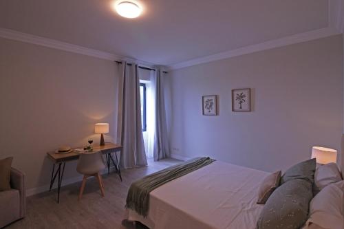 a bedroom with a bed and a table and a window at Solar Arco de São Jorge in Santana