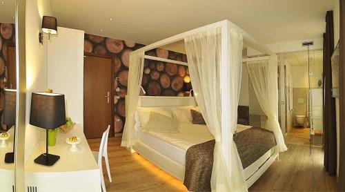 a bedroom with a canopy bed and a table with a lamp at Hotel Florida in Levico Terme