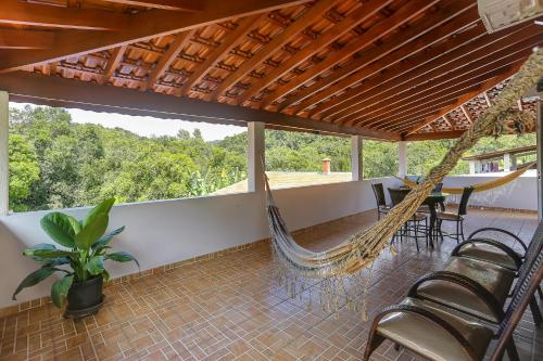 a porch with a hammock and a table and chairs at Casa São Luis in Lindóia