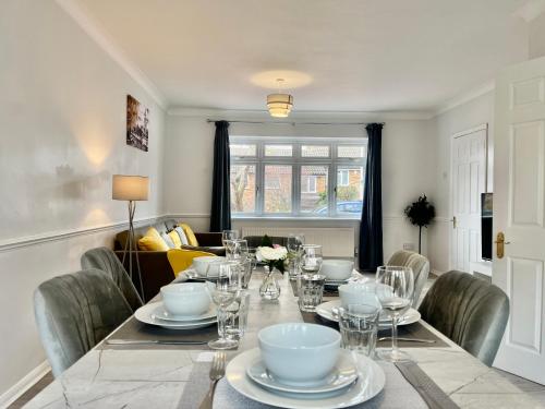 a dining room with a table with plates and glasses at Stylish 3 Bed Chigwell Home with Free Parking in Chigwell