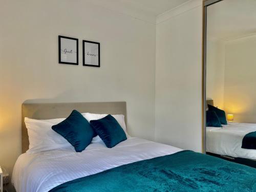 a bedroom with a bed with blue pillows and a mirror at Stylish 3 Bed Chigwell Home with Free Parking in Chigwell