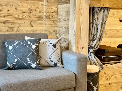 a couch with two pillows in a room with wooden walls at Il Ruscello Mountain Apartment in Madesimo
