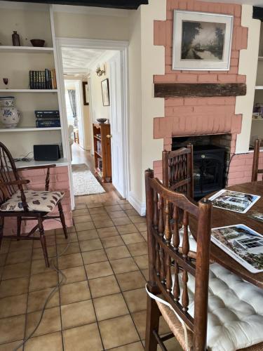 a living room with a fireplace and a table and chairs at Field Cottage in Whittlesey