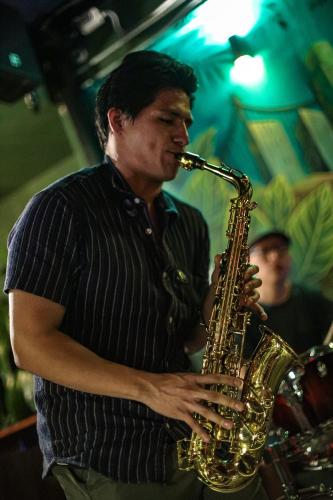 a man playing a saxophone in a room at Black Llama Hostel Miraflores in Lima