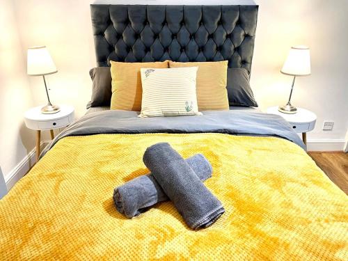 a bed with a yellow blanket with a stuffed animal on it at Cosmopolitan Stays in London