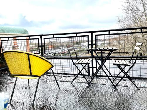 a yellow chair and a table on a balcony at Cosmopolitan Stays in London