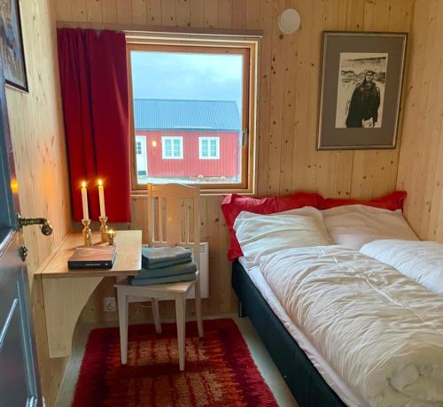 een slaapkamer met een bed en een tafel met een raam bij Edvardbua in Kvalnes