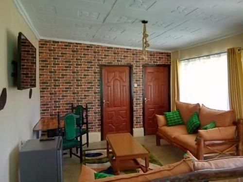 a living room with a couch and a brick wall at Wooden Knee Cottages Nanyuki in Nanyuki