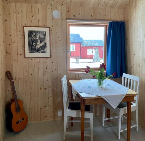 a dining room with a table and a guitar at Edvardbua in Kvalnes