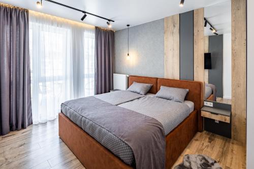 a bedroom with a bed and a large window at New designer apartments in Lviv