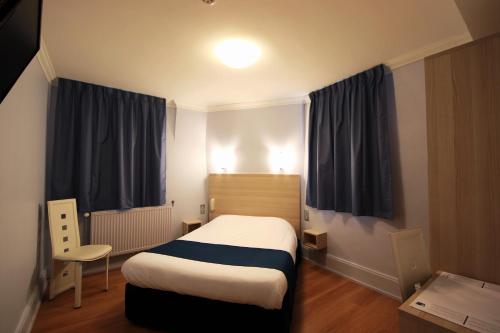 a small room with a bed and a chair in it at Hôtel De La Cathédrale in Reims