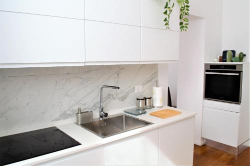 a white kitchen with a sink and a microwave at Eternal City Apartment in Rome