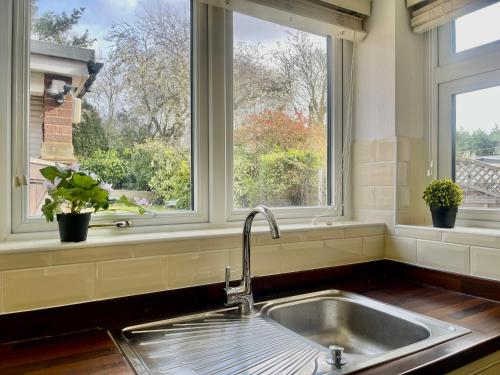a kitchen with a sink and two windows at Stylish 3 Bed Chigwell Home with Free Parking in Chigwell