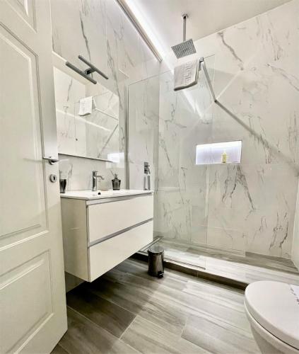 un bagno bianco con lavandino e doccia di Duomo Platinum Apartments a Napoli