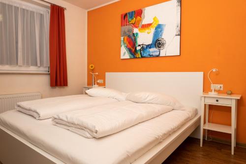 Bett in einem Zimmer mit orangefarbener Wand in der Unterkunft Art City Studio Kassel in Kassel