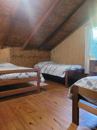 2 Betten in einem Zimmer mit Holzböden in der Unterkunft Cabañas rio ñilque in Ñilque