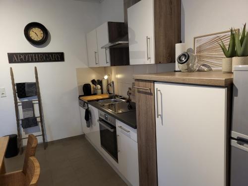 a kitchen with white cabinets and a sink and a clock at TKS-HOME Am Weiherplatz in Norken