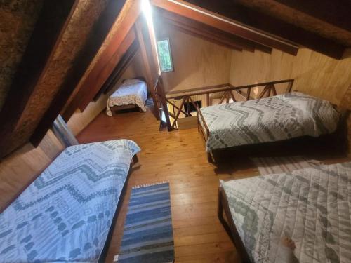 an attic room with three beds and a rug at Cabañas rio ñilque in Ñilque