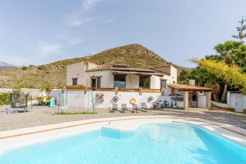 a villa with a swimming pool in front of a house at CORTIJO OHANA in Motril