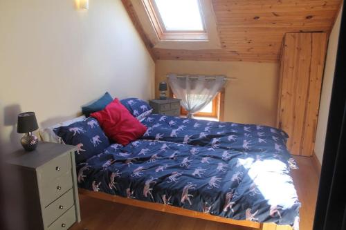 a bedroom with a bed with a blue comforter and a window at Le Miette, family house Sleeps 6 in La Celle-sous-Gouzon