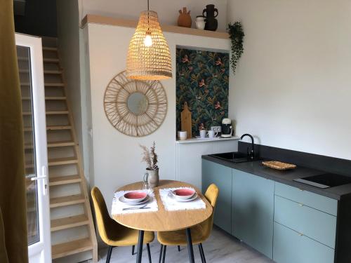 a kitchen with a table with chairs and a pendant light at Gîte Loufiosa Vannes in Vannes