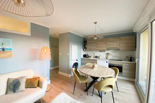 a living room with a table and chairs and a kitchen at Sainte-Cécile La Cabine Chic 4 personnes in Camiers