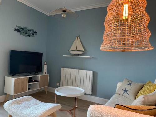 a living room with a couch and a tv at Sainte-Cécile La Cabine Chic 4 personnes in Camiers