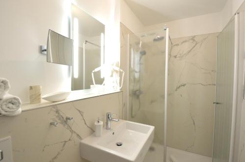 a white bathroom with a sink and a shower at Strandappartement in Binz in Binz