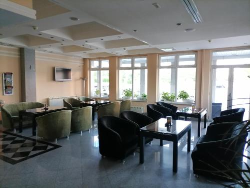 un restaurante con mesas, sillas y ventanas en Hotel Elegance, en Belgrado