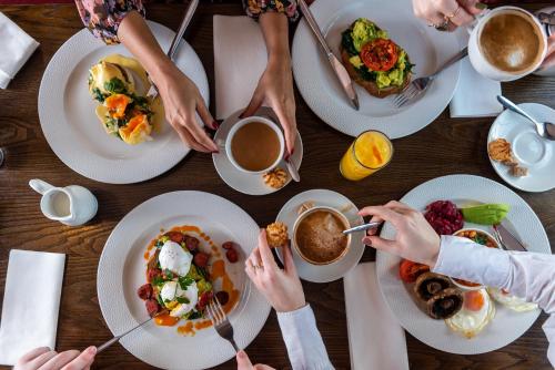 Un grupo de personas sentadas alrededor de una mesa comiendo comida en The Bell by Innkeeper's Collection, en Aston Clinton