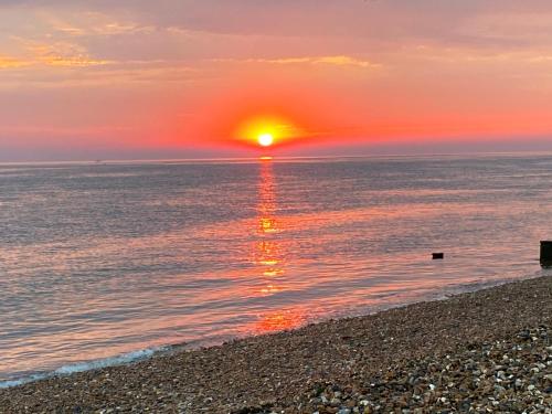 a sunset on the beach with the sun setting at Sea Street House in Kent