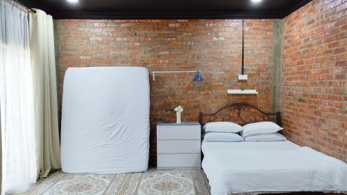 2 camas en una habitación con una pared de ladrillo en Studio Amani Permatang Pauh en Permatang Pauh