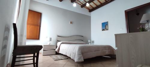 a white bedroom with a bed and a chair at Casolare Nelle Saline in Torre Nubia