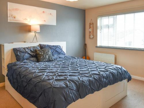 a bedroom with a bed with a blue comforter and a window at Breuddwydion Cymru welsh Dreams in Cemaes Bay