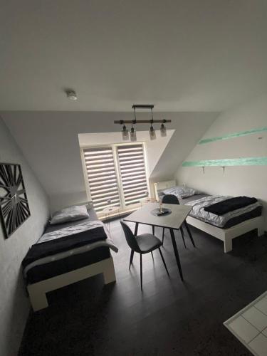 een zolderkamer met 2 bedden, een tafel en een raam bij PS-Projektentwicklung in Dortmund