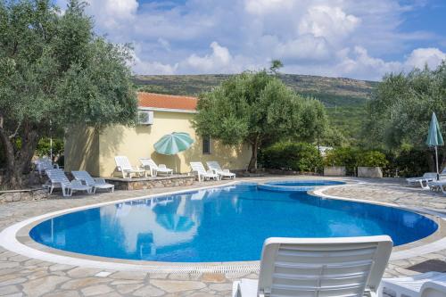 a swimming pool with chairs and umbrellas next to a house at Villa Thetis in Bigovo
