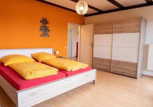 Schlafzimmer mit orangefarbenen Wänden und einem Bett mit gelben Kissen in der Unterkunft Art City Studio Kassel 4/8 in Kassel