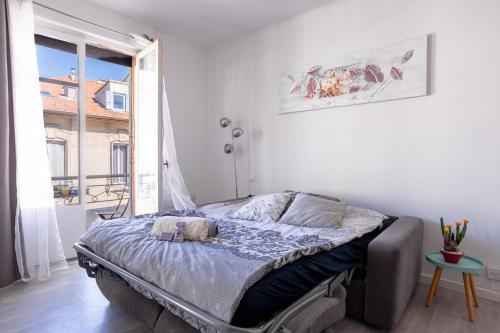 een bed in een witte kamer met een raam bij Cannes centre apartment with a balcony in Cannes
