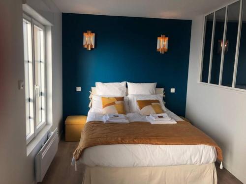 - une chambre avec un grand lit et un mur bleu dans l'établissement Maison Gabriel Appartement BULLE, à Abbeville