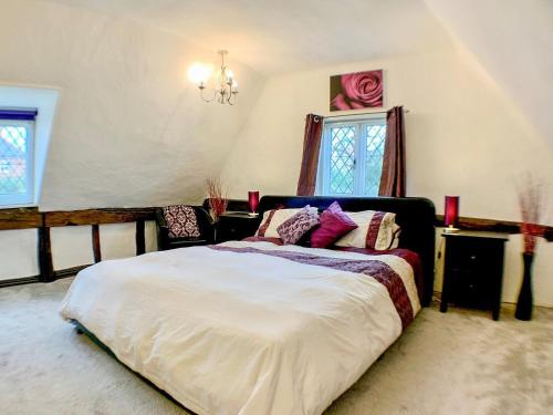 a bedroom with a large bed and a chandelier at Laburnham Cottage in Stowmarket