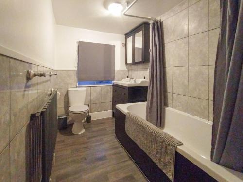 a bathroom with a tub and a toilet and a sink at Laburnham Cottage in Stowmarket