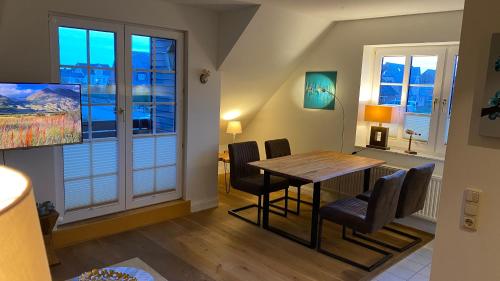 ein Esszimmer mit einem Tisch, Stühlen und einem Fenster in der Unterkunft Hotel Kiose - Ferienwohnungen in Wenningstedt-Braderup